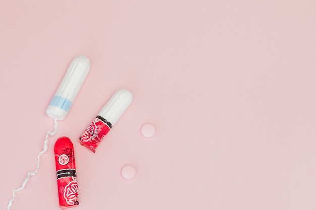 Tampons und Pillen auf einem rosa Hintergrund