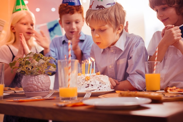 Tan concentrado. Niños encantados positivos de pie cerca de su amigo y estrechando las manos