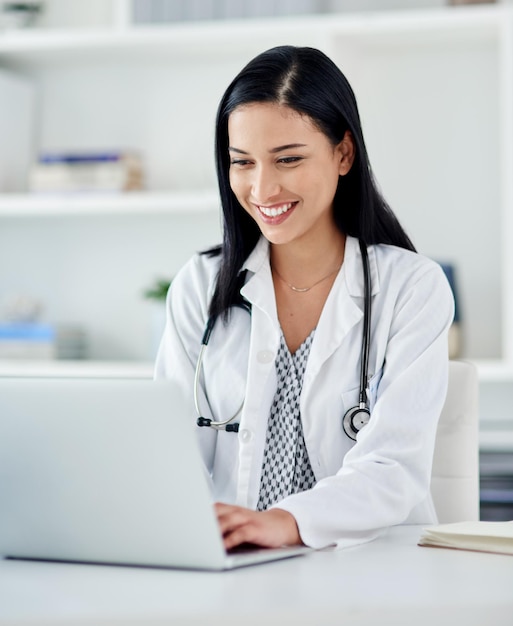 Tan eficiente como le gustaría que fuera su médico Foto de una joven doctora usando una computadora portátil en su escritorio