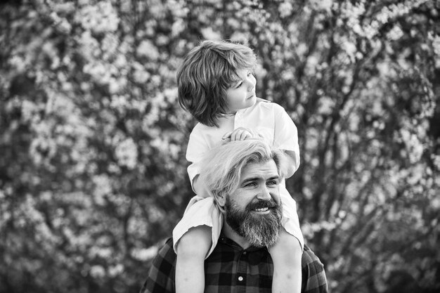 Tan feliz Papá guapo con su pequeño hijo lindo disfruta de la floración y la naturaleza juntos feliz día de la familia se acerca la primavera solo diviértete concepto de amor Padre alegre jugando con su hijo en el parque