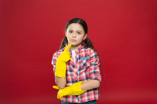 Tan fresco y tan limpio Niño pensativo use guantes de goma fondo rojo Trabajo doméstico Rutina de limpieza Servicio de limpieza Limpieza y saneamiento Limpiar Mantener el hogar limpio Casa limpia