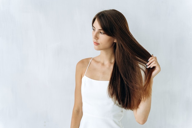 Tan libre como el viento. Retrato de mujer linda encantadora está de pie y mirando a otro lado mientras disfruta de la calidad de su cabello largo. Fondo aislado