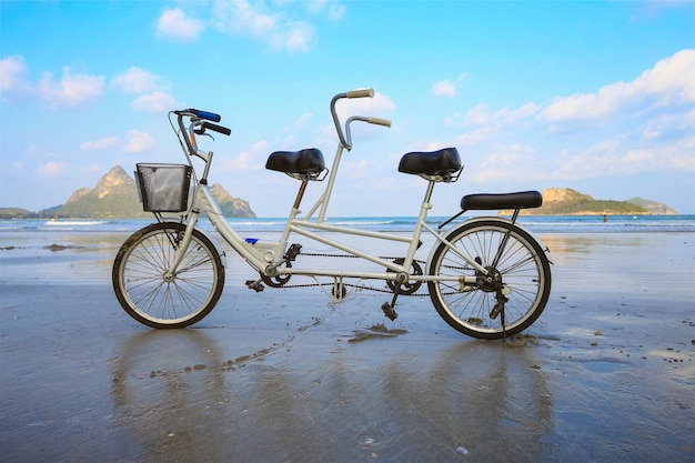 Tandemfahrradparken auf dem Strand mit ihm ist Reflexion