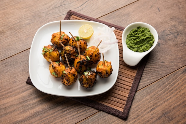 Tandoori aloo são batatas assadas com especiarias indianas. É um aperitivo de festa servido com chutney verde. foco seletivo