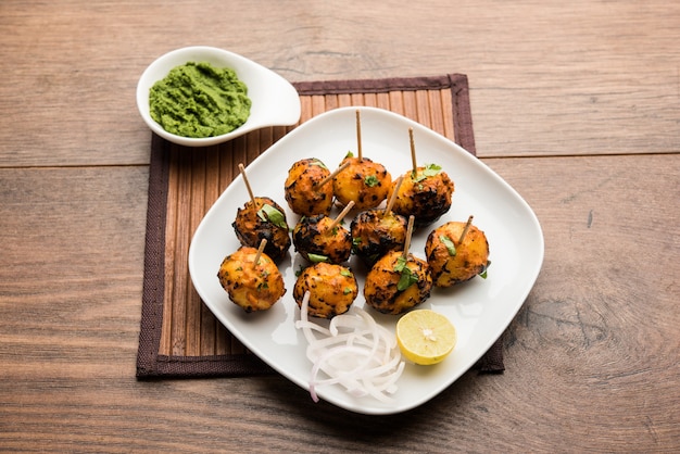 Tandoori aloo são batatas assadas com especiarias indianas. É um aperitivo de festa servido com chutney verde. foco seletivo