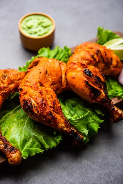 Tandoori Chicken ist ein Hühnchengericht, das durch Braten von in Joghurt und Gewürzen mariniertem Hühnchen in einem Tandoor- oder Lehmofen zubereitet wird, serviert mit Zwiebeln und grünem Chutney