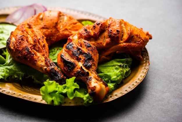Tandoori Chicken ist ein Hühnchengericht, das durch Braten von in Joghurt und Gewürzen mariniertem Hühnchen in einem Tandoor- oder Lehmofen zubereitet wird, serviert mit Zwiebeln und grünem Chutney