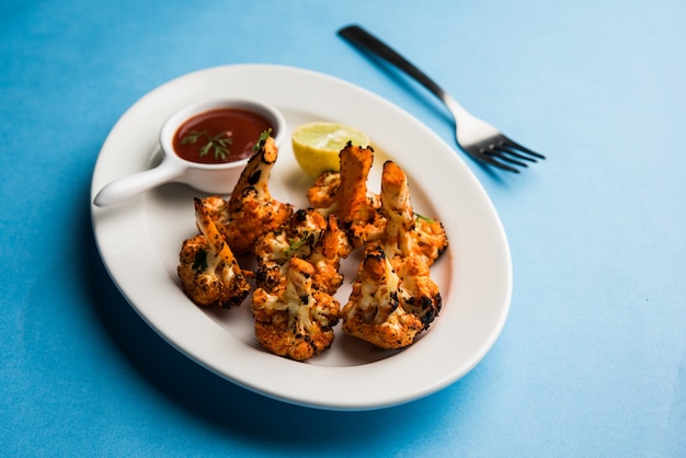 Tandoori Gobi o coliflor asada Tikka es un plato seco elaborado asando coliflores en Oven, Tandoor. Es un plato popular de la India. servido con salsa de tomate. enfoque selectivo