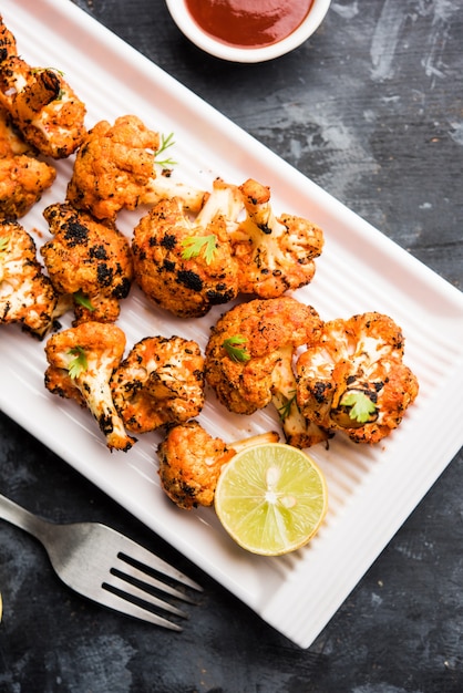 Foto tandoori gobi oder gerösteter blumenkohl tikka ist ein trockenes gericht, das durch rösten von blumenkohl im ofen, tandoor, hergestellt wird. es ist eine beliebte vorspeise aus indien. mit ketchup serviert. selektiver fokus