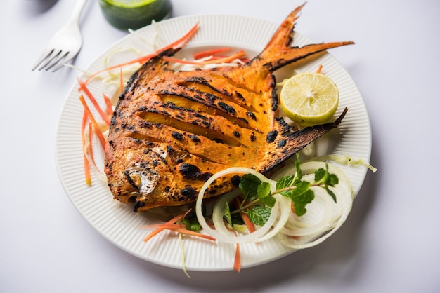 Tandoori Pomfret Fisch im Lehmofen gegart und mit Zitronen-, Minze-, Kohl- und Karottensalat garniert