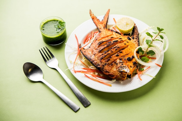 Tandoori Pomfret Fisch im Lehmofen gekocht und mit Zitronen-, Minze-, Kohl- und Karottensalat garniert. Selektiver Fokus