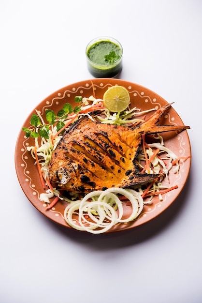 Tandoori Pomfret Fisch im Lehmofen gekocht und mit Zitronen-, Minze-, Kohl- und Karottensalat garniert. Selektiver Fokus