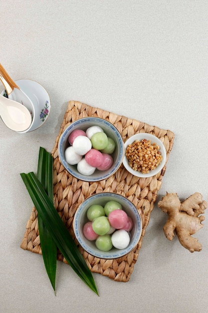 Tang Yuan (Wedang Ronde), bolas de bola de masa hervida de arroz glutinoso chino con jarabe de jengibre y azúcar en rojo chino sobre fondo rojo para el solsticio de invierno, el Año Nuevo o la comida del Festival de los Faroles. Copia espacio