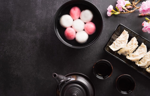 Tang Yuansweet Dumplings Balls eine traditionelle Küche für Midautumn Dongzhi Wintersonnenwende und chinesisches Neujahr mit Pflaumenblüte und Tee auf pastellfarbenem Hintergrund