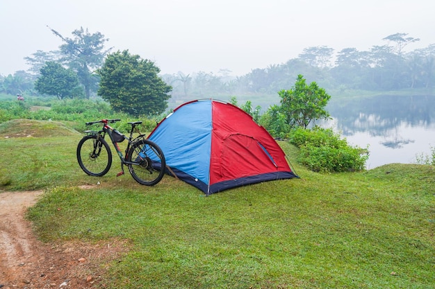 Foto tangerang, indonésia, 20 de setembro, acampar com barraca de caminhada na grama, à beira do lago, atmosfera nebulosa