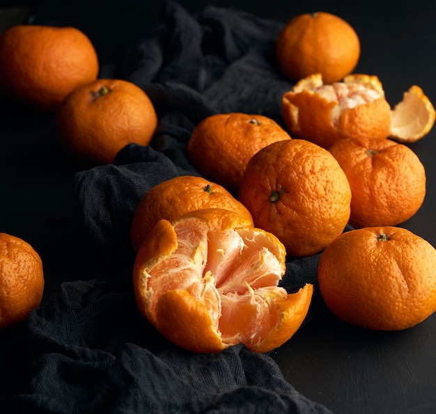 Tangerina descascada e laranja madura e um monte de frutos inteiros redondos com casca