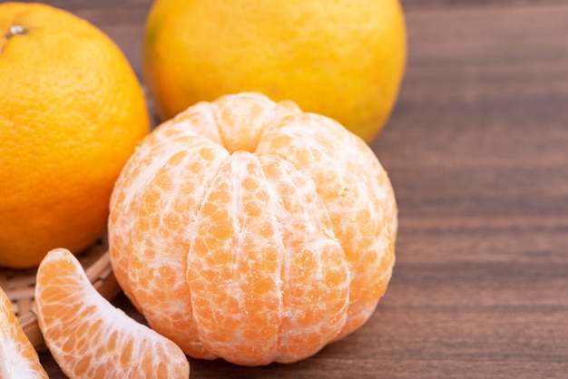 Foto tangerina fresca e linda cor laranja na peneira de bambu, mesa de madeira escura. fruta tradicional sazonal do ano novo lunar chinês, close-up.