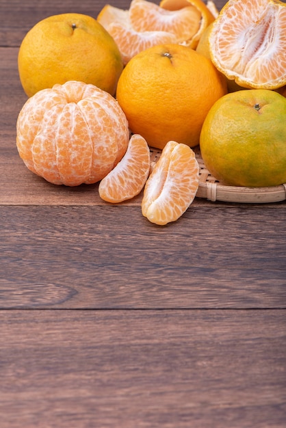 Tangerina fresca e linda cor laranja na peneira de bambu, mesa de madeira escura. Fruta tradicional sazonal do ano novo lunar chinês, close-up.