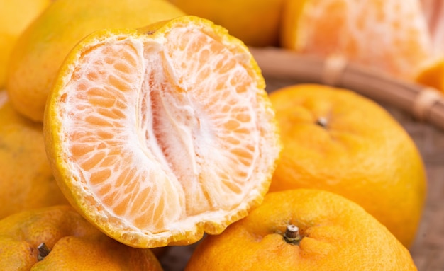 Tangerina fresca e linda de cor laranja na peneira de bambu sobre uma mesa de madeira escura