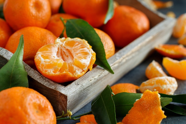 Tangerinas com folhas em uma caixa em um fundo escuro