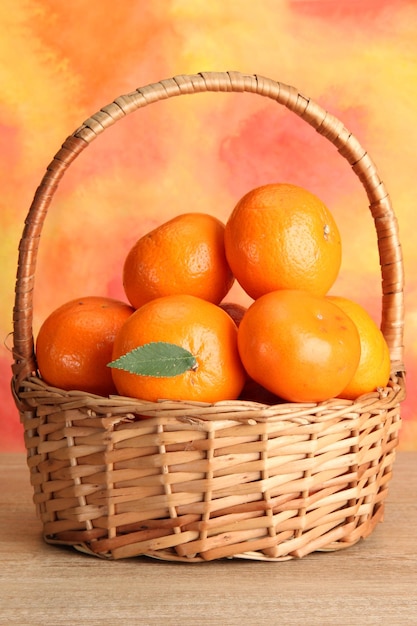 tangerinas com folhas em uma linda cesta na mesa de madeira em fundo laranja