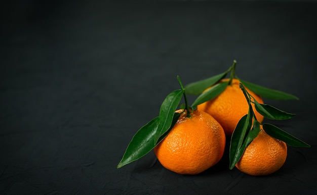 Tangerinas com folhas no fundo preto.