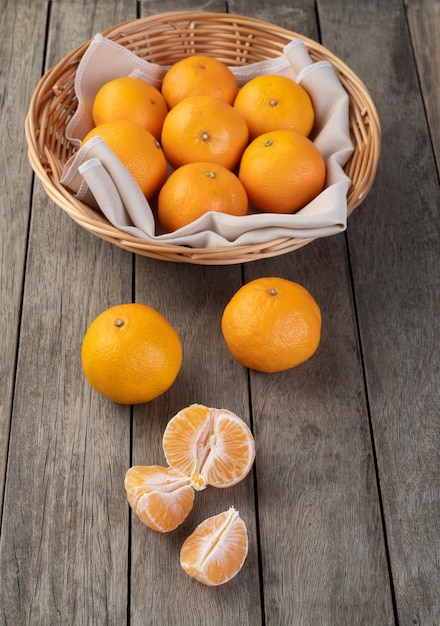 Tangerinas com frutas cortadas sobre a mesa de madeira.