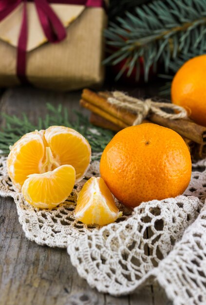 Tangerinas com pauzinhos de canela e uma caixa de presente com galhos de abeto de Natal em uma mesa