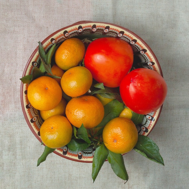 Tangerinas e caqui repousam em um belo prato.