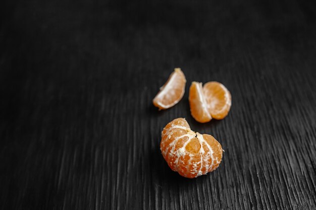 Tangerinas em um fundo preto. Muitas frutas frescas - tangerinas.