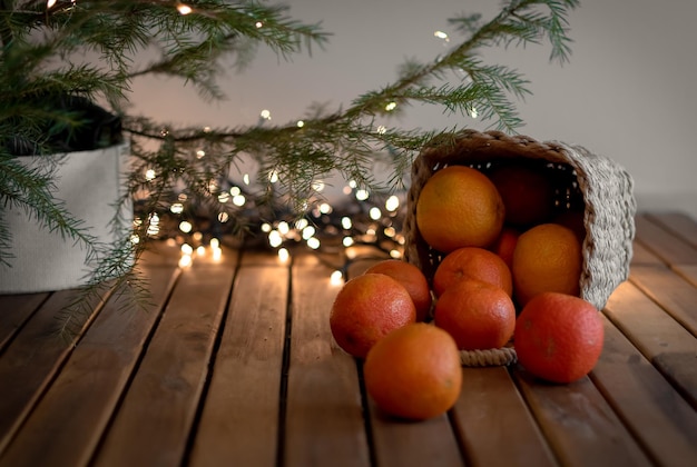tangerinas em uma mesa de madeira debaixo de uma árvore de Natal em um fundo de luzes