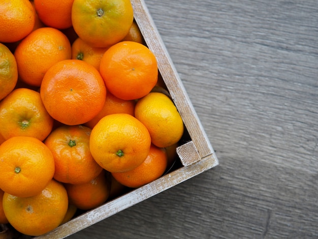 Tangerinas frescas em uma caixa velha. No fundo de madeira.