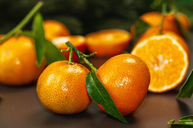 Tangerinas (laranjas, tangerinas, clementinas, frutas cítricas) com folhas e galhos de abeto. Fundo de pedra preta, postura plana festiva, close-up