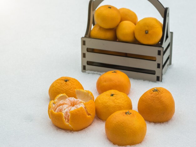 Tangerinas maduras na neve e em uma caixa de madeira. frutas cítricas populares.