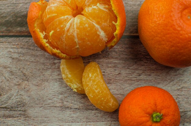 Tangerinas, tangerina descascada e fatias de tangerina sobre uma mesa de madeira branca. copie o espaço