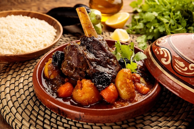 Tangina marroquí de cordero y verduras con pan servido en un plato aislado en una vista lateral de fondo de madera