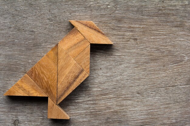 Tangram de madera como forma de pájaro en el fondo de madera vieja