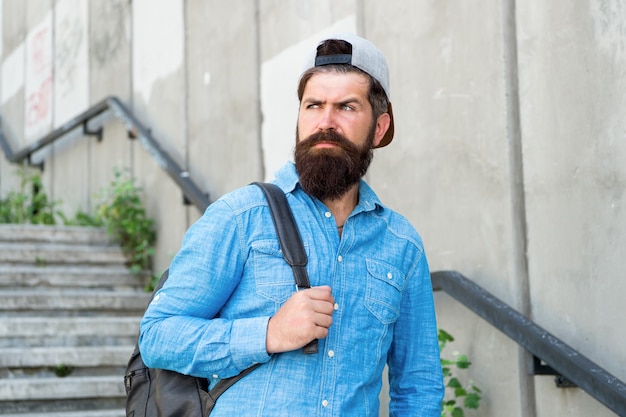 Tanken Sie Ihre Seele mit Reisen. Zuversichtlicher Mann geht Straße. Männerfriseurpflege. brutaler Hipster mit Reiserucksack. Wanderabenteuerkonzept. urbanen Stil. Reifer Hipster mit Bartreisender. Bärtiger Mann.