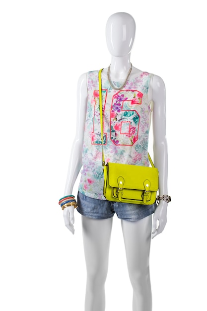 Tanktop mit Limetten-Geldbörse. Weibliche Schaufensterpuppe mit Kalkbeutel. Sommer-Outfit mit bunter Handtasche. Stilvoller Look für junges Mädchen.