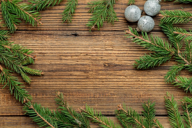 Tanne, Fichtenzweige und Christbaumspielzeug auf braunem Holz