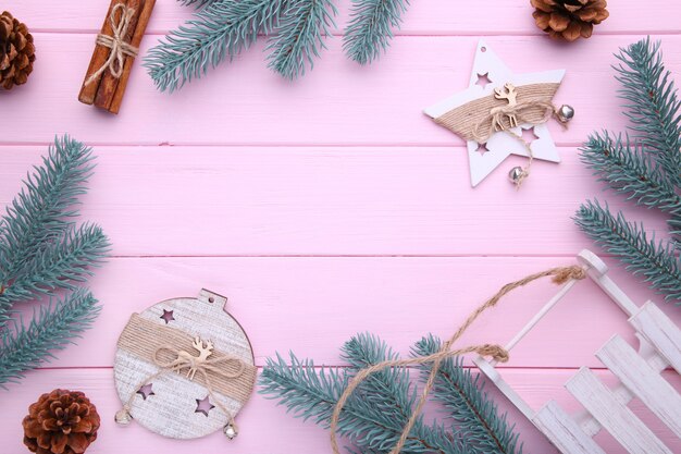 Tannenbaumaste mit Weihnachtsspielwaren auf rosa Hintergrund