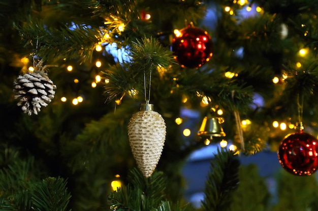 Tannenzapfen am Weihnachtsbaum mit Girlande auf dunklem Hintergrund. Bokeh-Effekt für das neue Jahr
