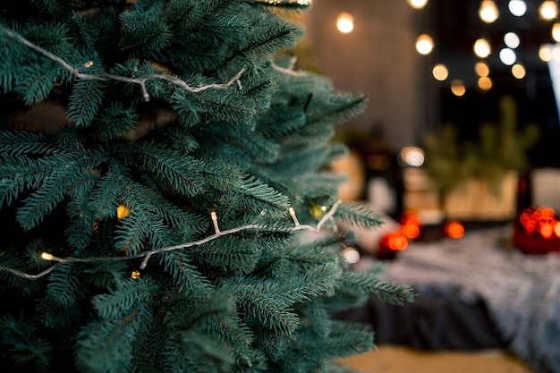 Tannenzweig mit Kugeln und festlichen Lichtern auf dem weihnachtlichen Hintergrund mit Funkeln Ausgeschnittener Blick auf den Tannenbaum mit Lichtern