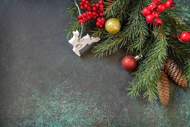 Tannenzweig und Weihnachtsdekorationen mit auf einem dunkelgrünen Steinhintergrund Feiertagskonzept