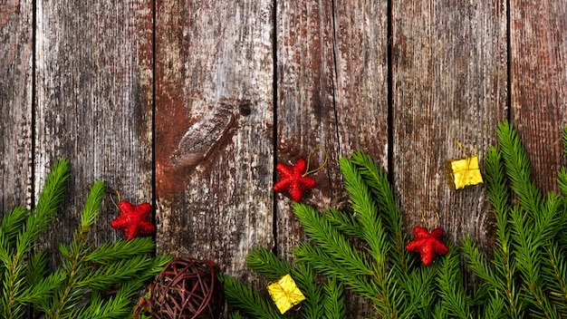 Tannenzweige auf einem Holztisch. Weihnachtsbaumschmuck. Rote glänzende Sterne, Weihnachtsspielzeug