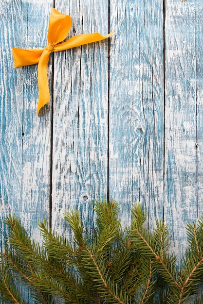 Tannenzweige und goldene Bandschleife auf einem blauen hölzernen Hintergrund, kopieren Raumoberansicht