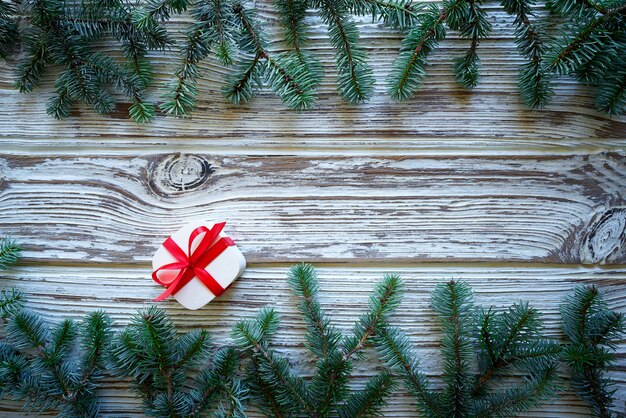 Tannenzweigweihnachten und -geschenk auf weißem Holz