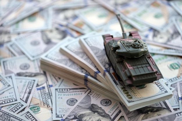 Tanque de brinquedo sobre nós notas de cem dólares notas de banco o conceito de custos de guerra gastos militares e