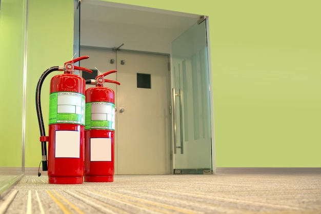 Tanque de extintor rojo en la puerta de salida del edificio.