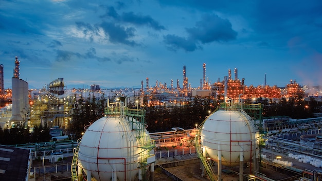 Tanques de esfera de armazenamento de gás e oleoduto na planta industrial de refinaria de petróleo e gás com propriedade de indústria de iluminação de brilho no crepúsculo